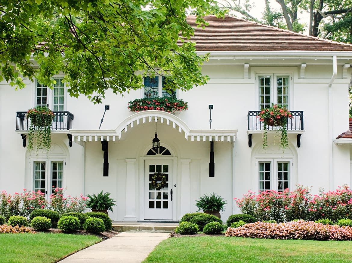 White two-story house with balconies and a landscaped front walk